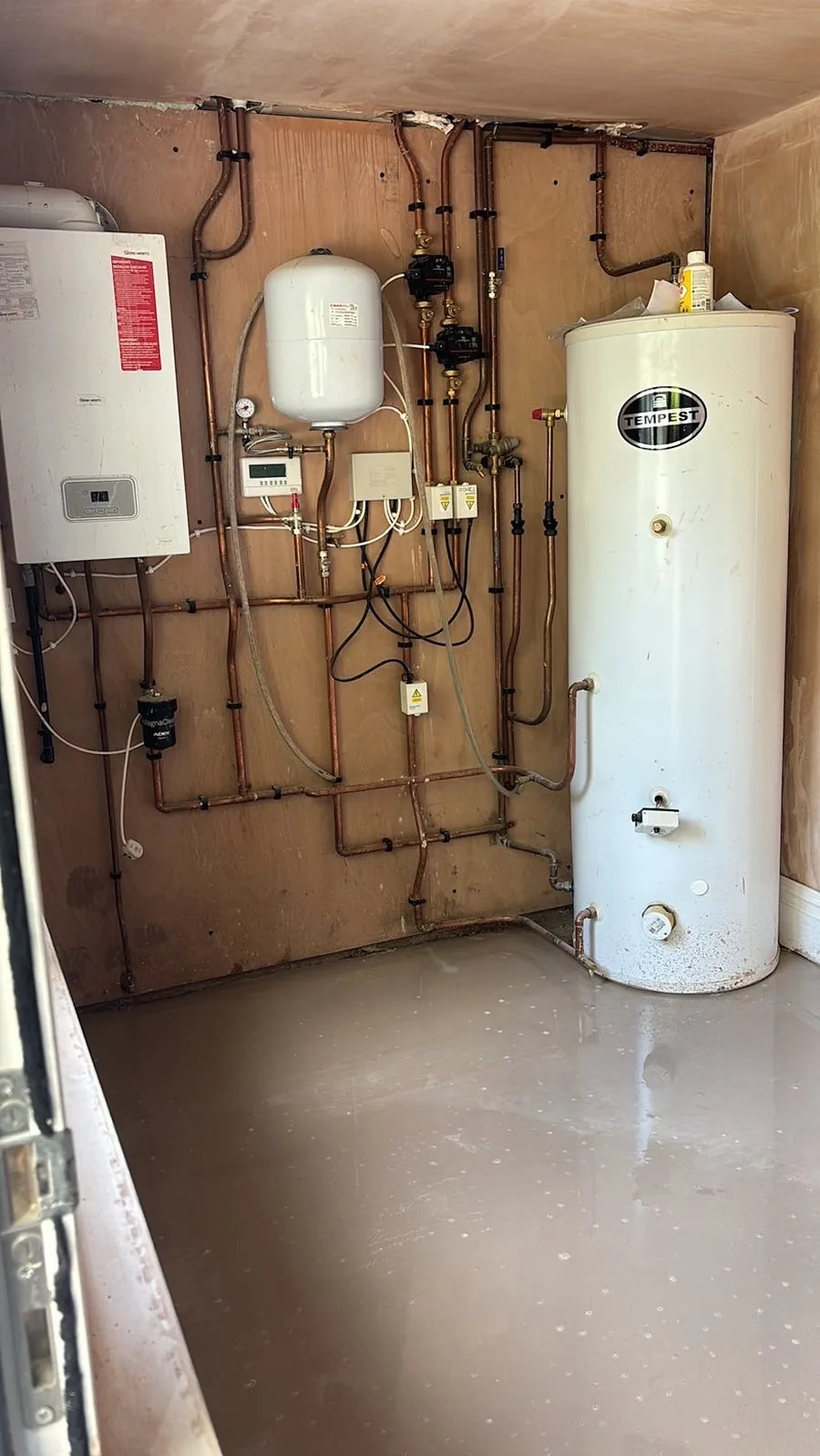 Glow-worm boiler and Tempest unvented hot water cylinder in a plant room, with an expansion vessel, pumps, zone valves and copper pipework clipped to the wall