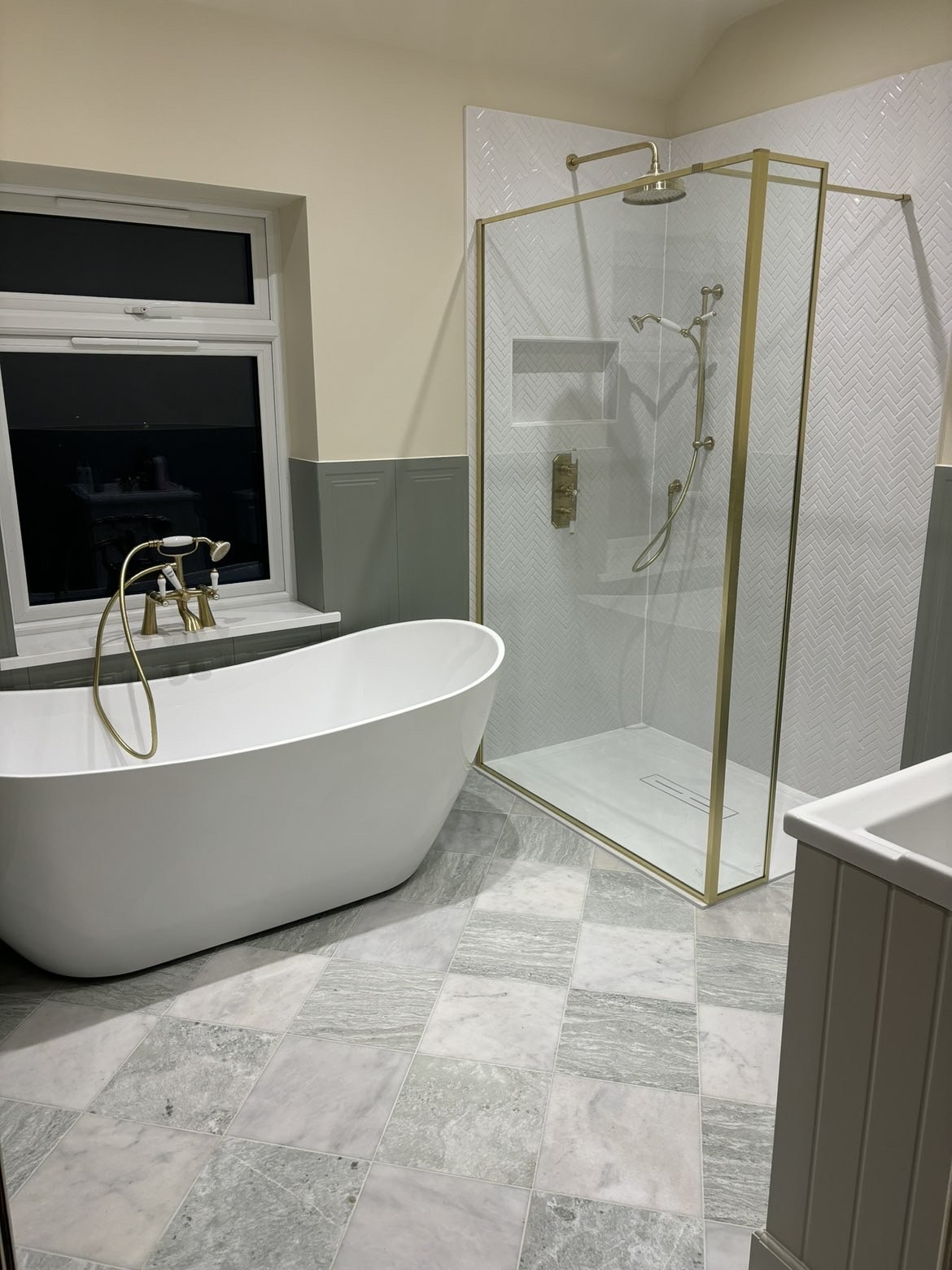Traditional bathroom refit with freestanding slipper bath and brushed brass walk-in shower enclosure over grey marble-effect floor tiles