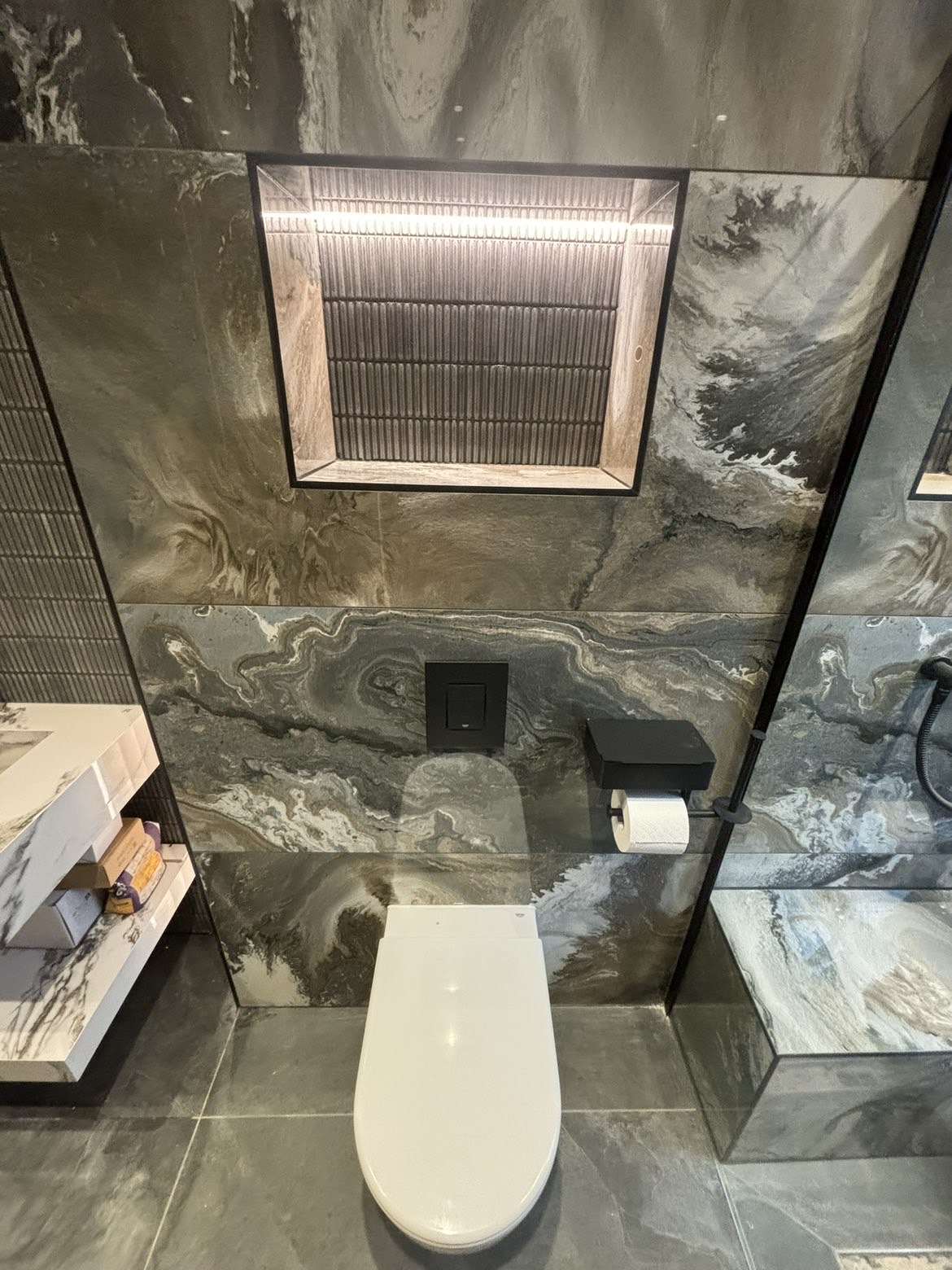 Wall-hung WC with concealed cistern, black flush plate and lit mirrored recess